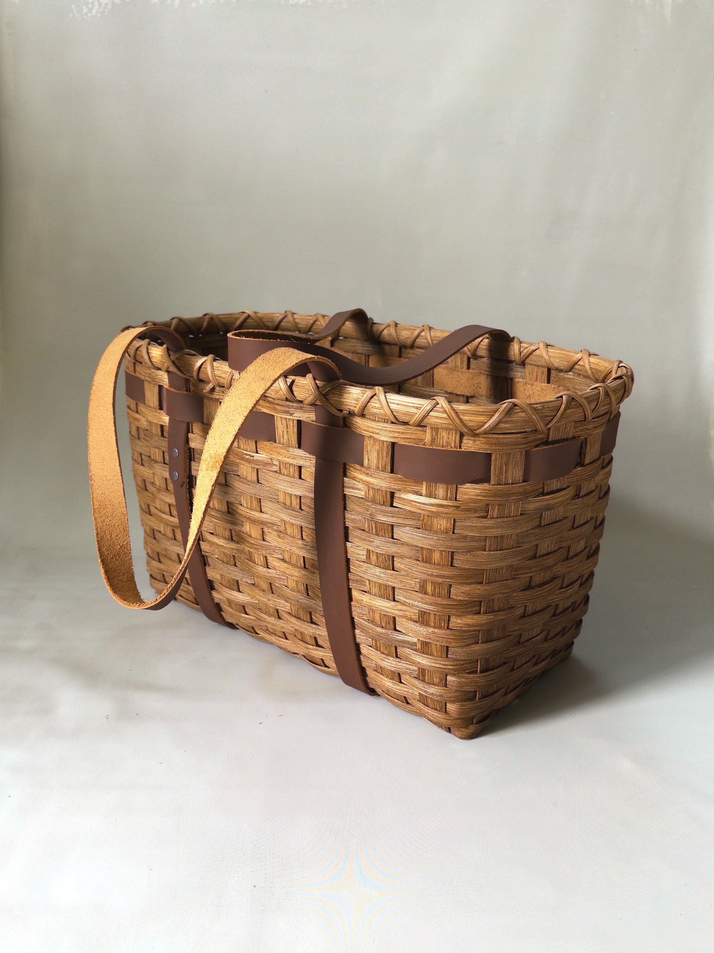 Two handwoven Leather Handled Tote Baskets with brown leather handles